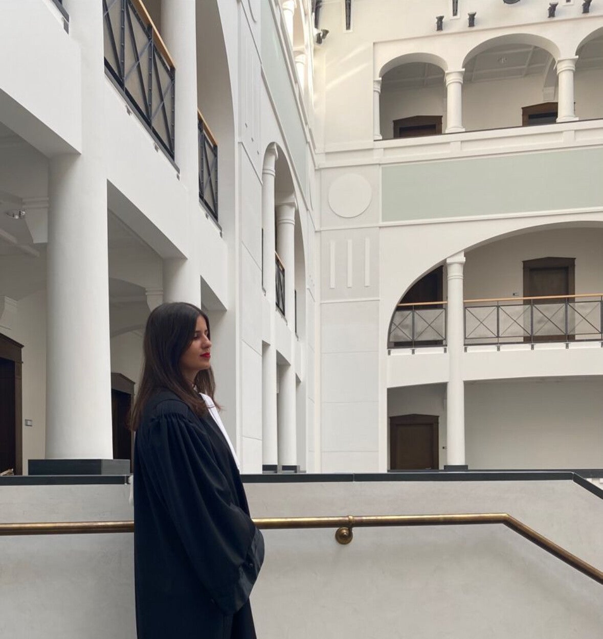 Maître Jamila Bouayss en robe d'avocate, sous des arcades blanches